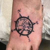 a compass tattoo on the foot of a woman