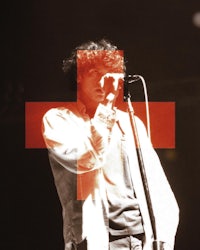 a man holding a microphone with a red cross on it