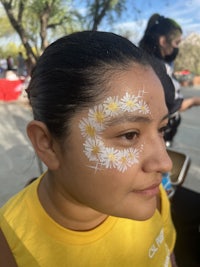 a woman with a white face painted with daisies
