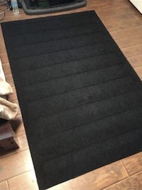 a black rug on a wooden floor in a room