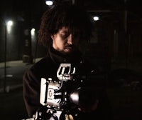 a man with curly hair holding a camera at night