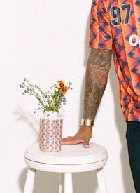 a man standing on a stool holding a vase of flowers