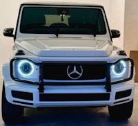a white mercedes g-class parked in a garage