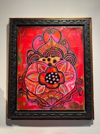 a framed painting of a red flower on a wall