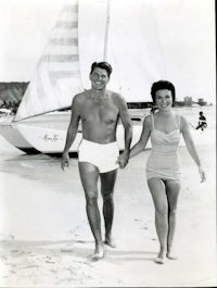 an old black and white photo of a couple holding hands on the beach
