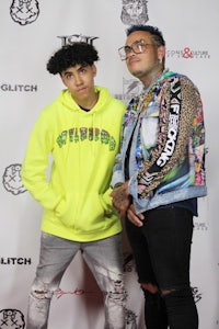 two young men standing next to each other on a red carpet