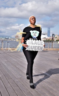 a woman holding a black queen sign on a boardwalk