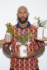 a man with a beard holding two pots of flowers