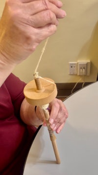 a woman spinning a wooden wheel on a table