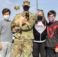a group of people wearing face masks posing with a dog