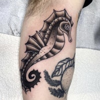 a seahorse tattoo on a man's forearm