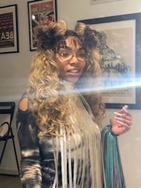a woman wearing a wig and glasses is standing in front of a mirror