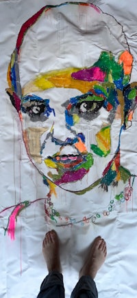 a person standing in front of a colorful painting of a person's face