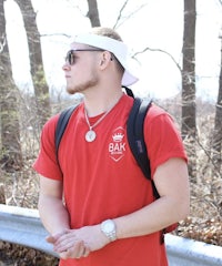 a young man wearing a red t - shirt and sunglasses