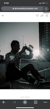 a man is sitting on a ledge with a phone in his hand