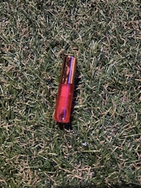 a red lipstick laying on the grass
