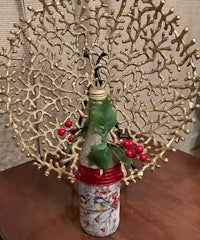 a bottle decorated with holly and birds on a table