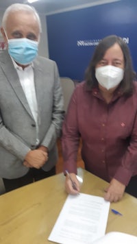 two people wearing face masks signing a document