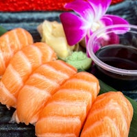 a plate of sushi with sauce and a flower