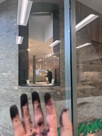 a person's hand in front of a glass window