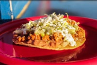 a red plate with a taco on it