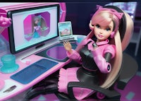 a barbie doll sitting in front of a computer