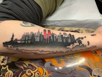 a tattoo of a new york city skyline on a person's forearm