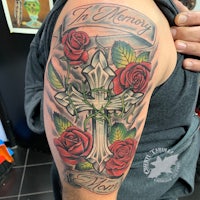 a tattoo of a cross and roses on a man's arm