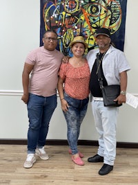 three people standing in front of a painting