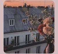 flowers in a vase on a balcony overlooking the eiffel tower