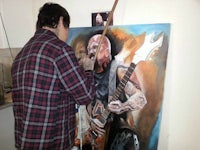 a man painting a portrait of a man with a guitar