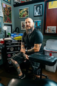 a man sitting on a chair in a tattoo shop
