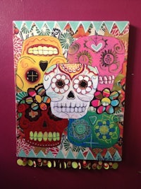 a colorful painting of sugar skulls hanging on a wall