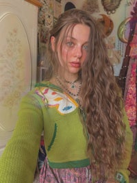a girl with long curly hair in a green sweater