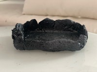 a black ashtray on a table next to a couch