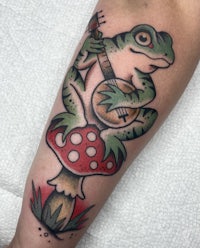 a tattoo of a frog playing a guitar on a mushroom