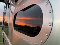 the window of an airstream trailer with a sunset in the background