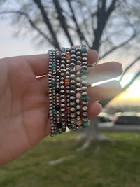 a person holding a bracelet with turquoise and silver beads