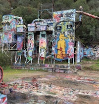 a graffiti covered building in the middle of a field