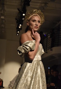 a model wearing a gold dress on the runway