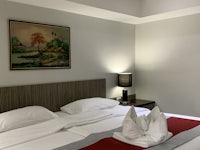 a room with a white bed and a painting on the wall