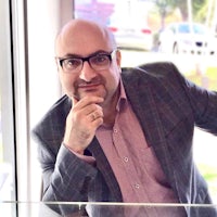 a bald man in glasses is leaning against a glass window
