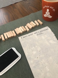 a piece of paper on a table next to a cell phone and wooden blocks