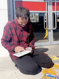 a man sits on the ground in front of a store