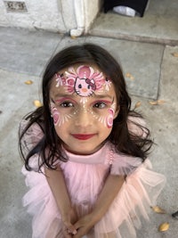 a little girl wearing a pink tutu and pink face paint