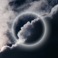 an eclipse in the sky with clouds in the background