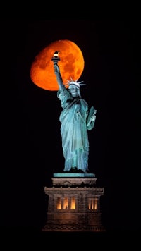a statue of liberty with a full moon in the background