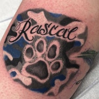 a tattoo of a paw print with the name rascal