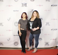 two women standing on a red carpet