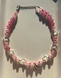 a pink beaded bracelet with silver charms
